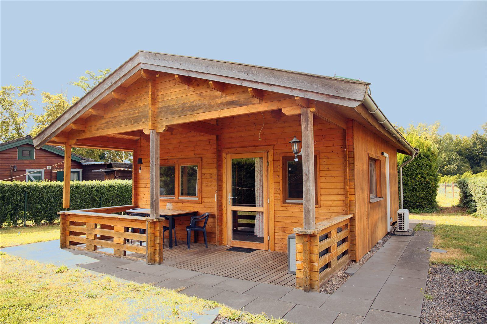 Das Blockhaus von au&szlig;en mit &uuml;berdachter Terrasse und Sitzplatz